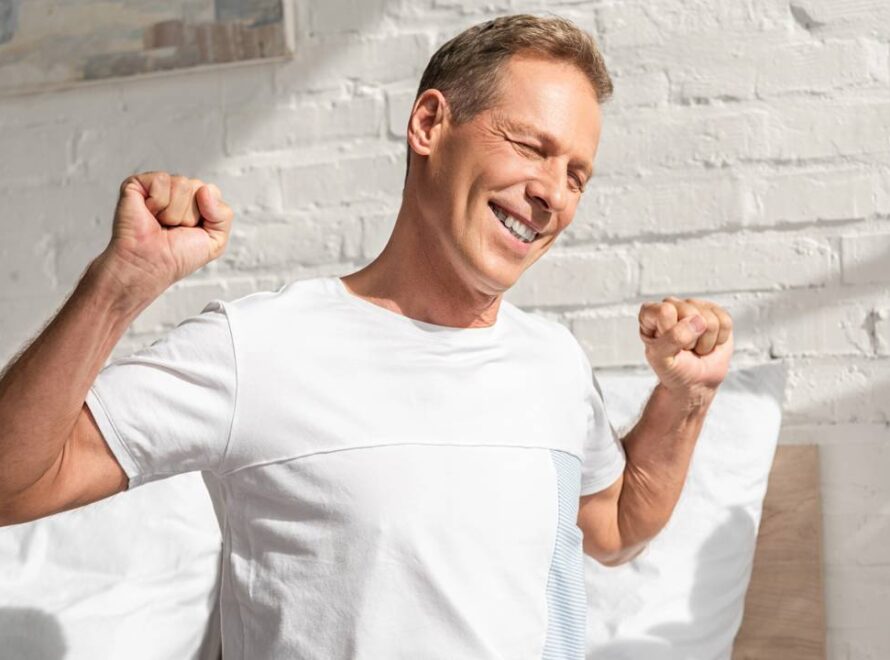 Homem levantando da cama feliz após alongamento matinal