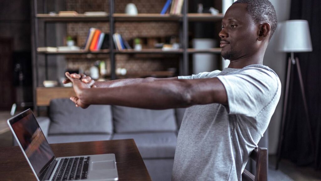 Homem se alongando ao pc durante rotina de home office