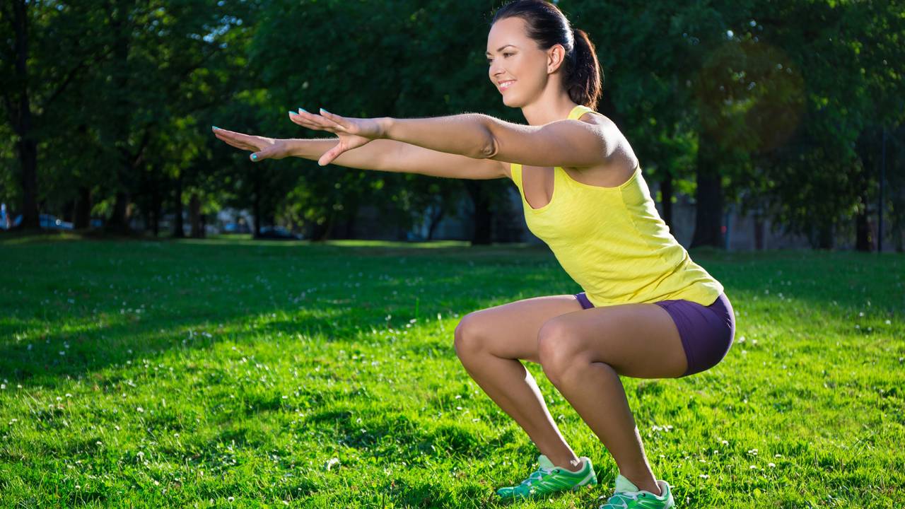 Mulher agachando em atividade física ao ar livre