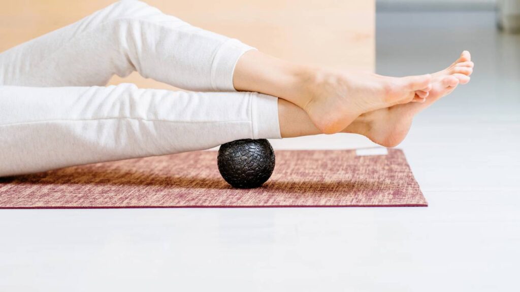 Mulher fazendo pilates com bola de massagem