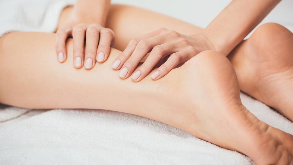 Mulher recebendo massagem nas pernas durante sessão terapêutica