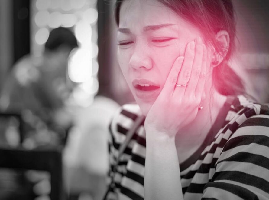 Mulher sofrendo com dores na região da face por complicação na Articulação Temporomandibular