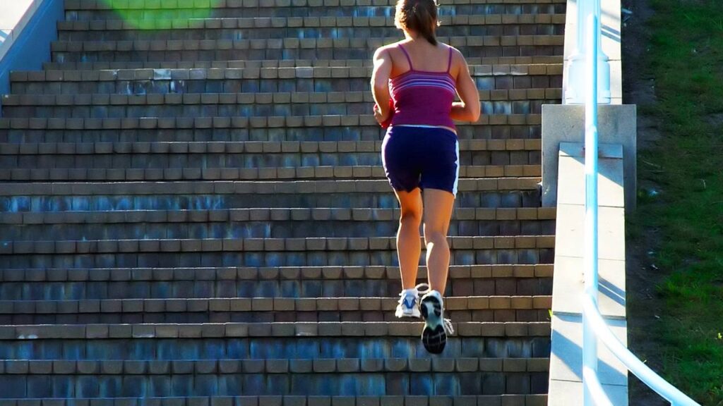 Mulher subindo escadas para se exercitar
