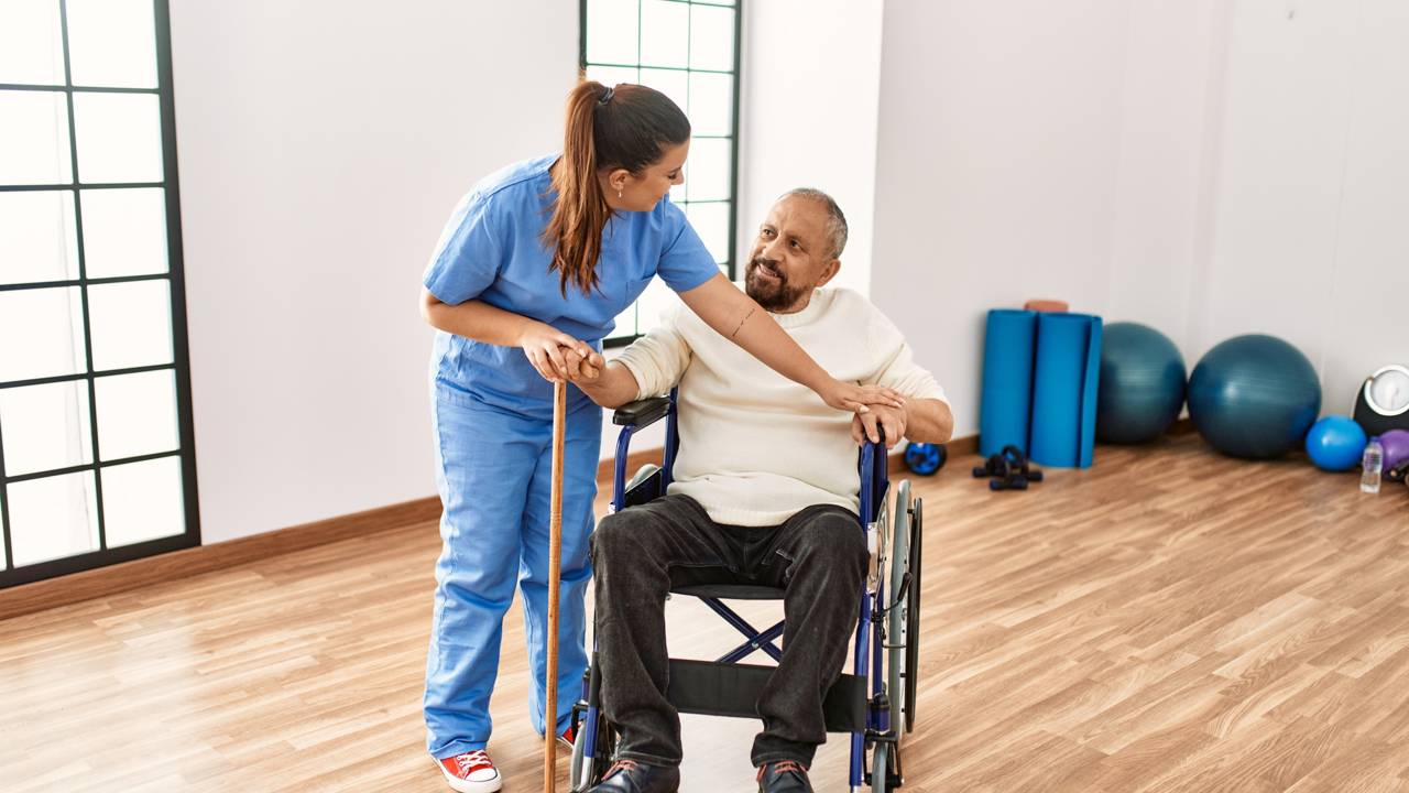 Fisioterapeuta ajudando na reabilitação de senhor de idade na cadeira de rodas