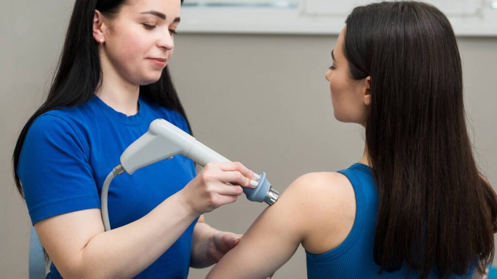 Paciente passando por procedimento com ondas de choque em clínica de fisioterapia