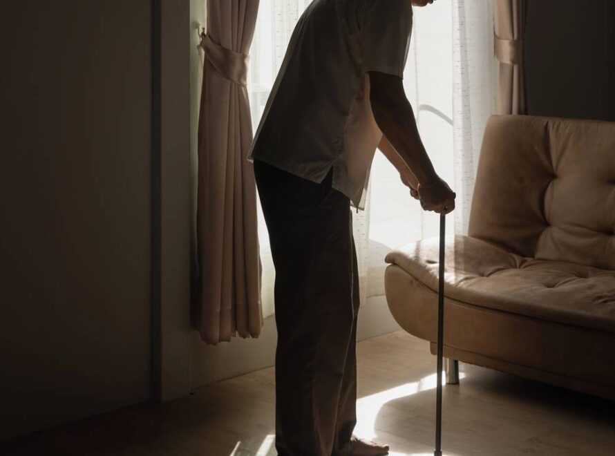 Idoso de pé em casa na sala com bengala
