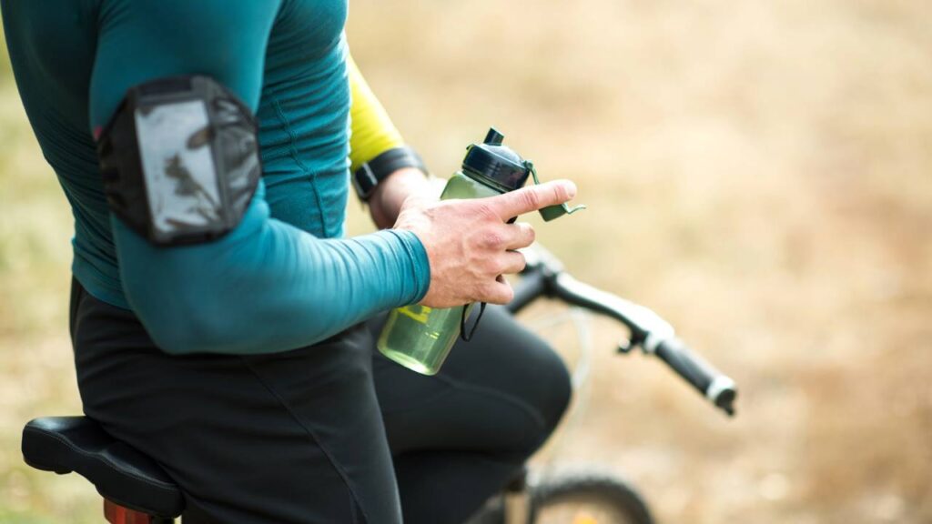 Ciclista segurando garrafa de água ao lado de sua bike