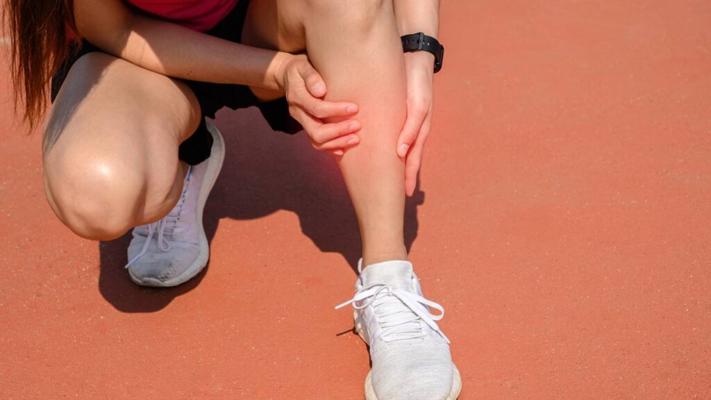 Mulher com dores na canela durante treino