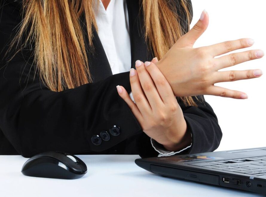 Mulher com dores no pulso por uso prolongado e não ergonômico do mouse