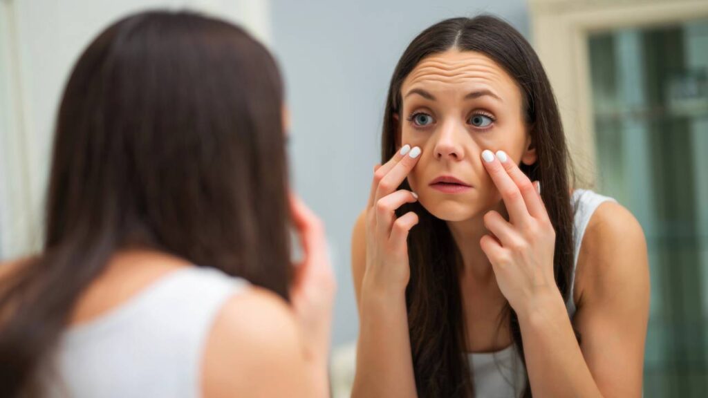 Mulher observando as bolsas sob seus olhos após acordar