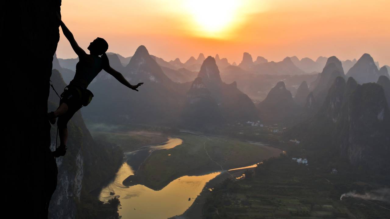 Mulher realizando escalada profissional em alta montanha ao por do sol