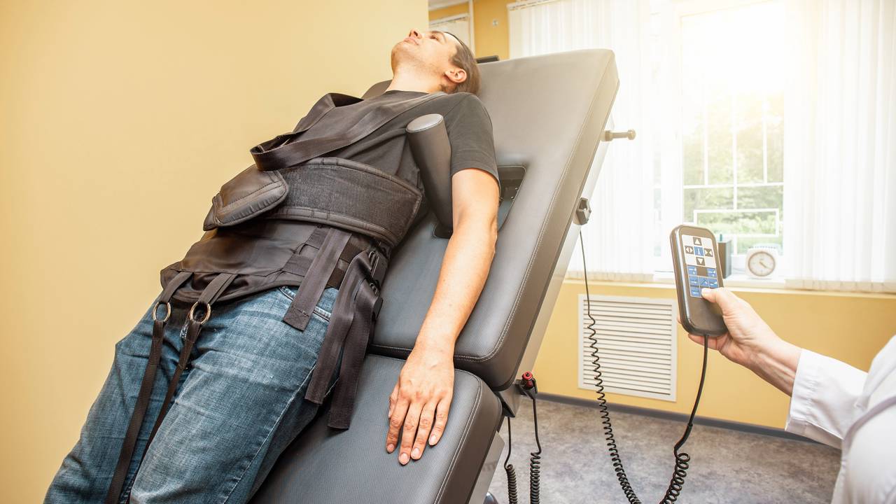 Paciente realizando descompressão em mesa de tração